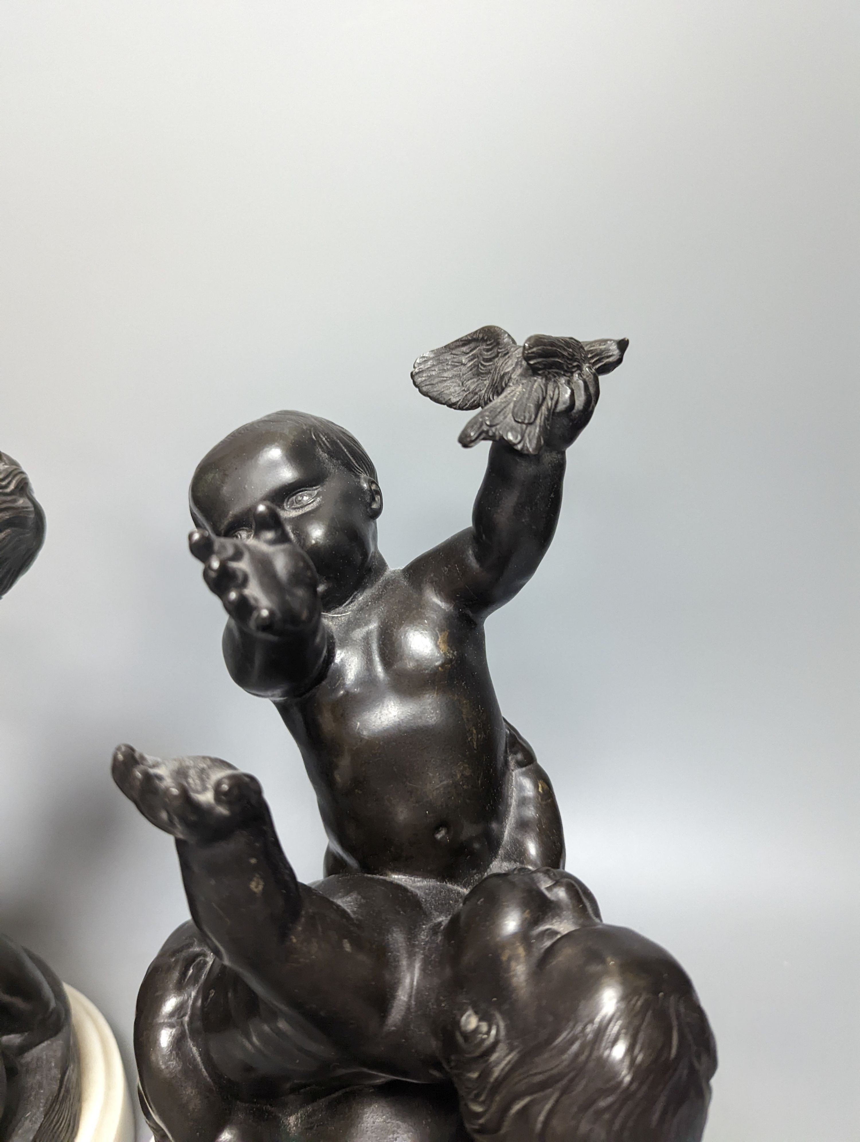 A pair of bronze figure groups, trio of putto, on white marble plinths, tallest 26cm